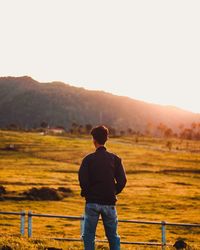 Rear view of man standing on field against sky