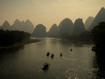 Scenic view of river by silhouette mountains against sky