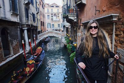 Portrait of woman standing in balcony over canal in city