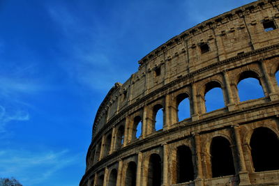 Low angle view of coliseum against blue sky