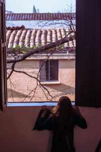 Rear view of woman standing against building