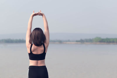 Rear view of woman standing in water against sky