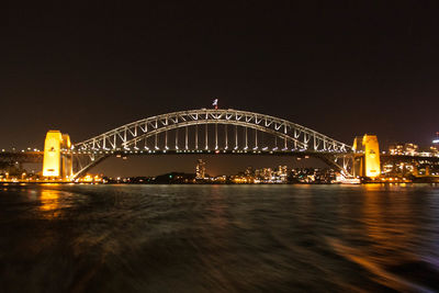 Illuminated bridge over river at night