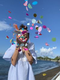 Woman with balloons in sea against sky