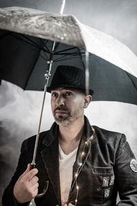 Close-up of man holding umbrella against sky