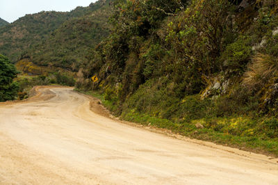 Empty road leading towards green mountains