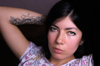 Close up portrait of lovely brunette girl with makeup and tattoo on her arm