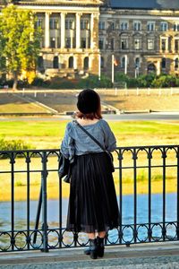 Rear view of woman standing on railing in city