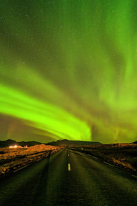 Scenic view of landscape against aurora filled sky at night