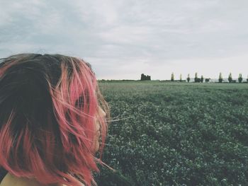 Woman with dyed hair on landscape against sky