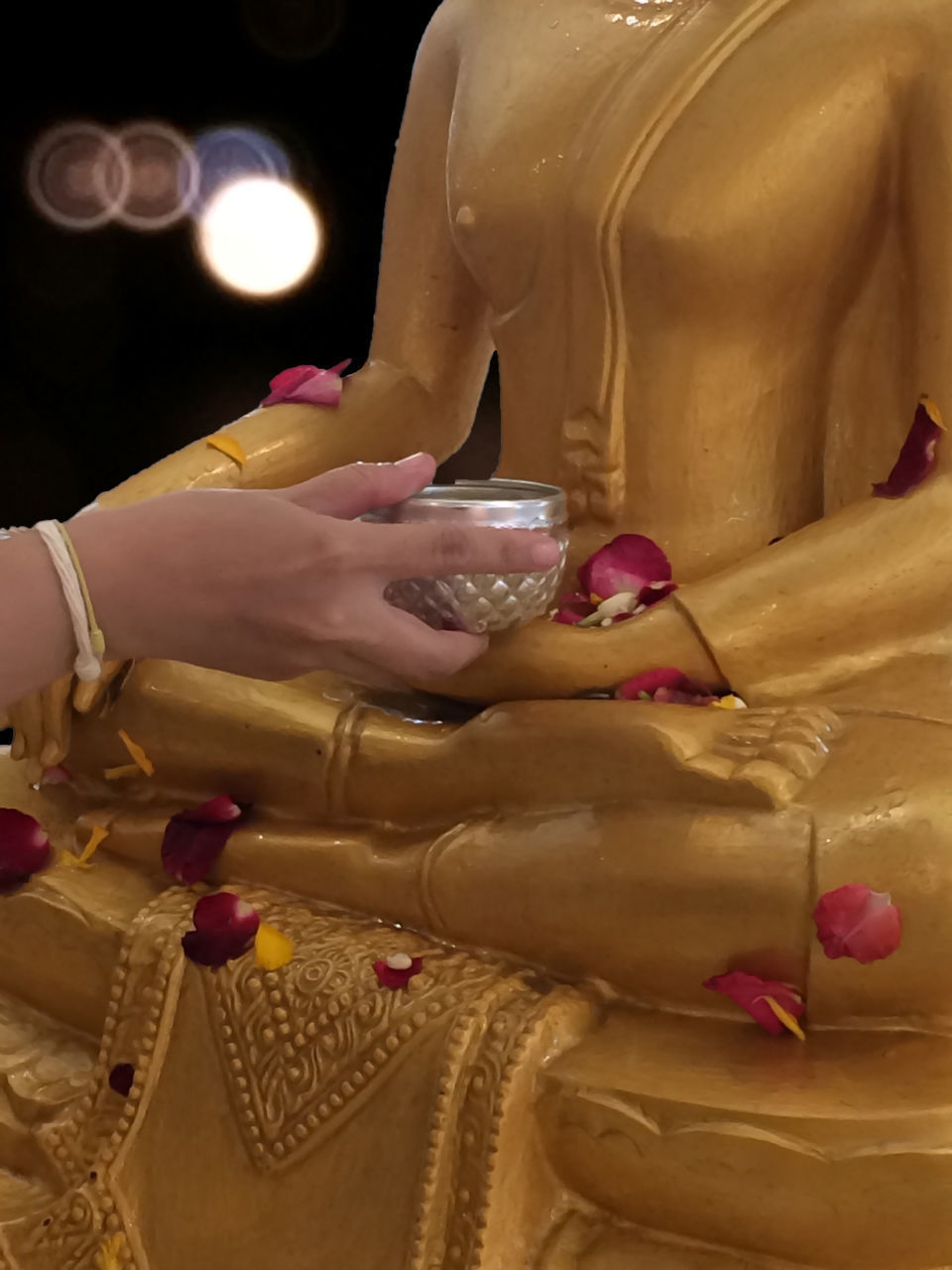 CLOSE-UP OF WOMAN HOLDING SCULPTURE OF BUDDHA
