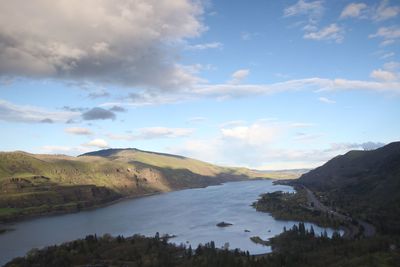 Scenic view of river and mountains against cloudy sky