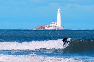 Man on lighthouse by sea against sky