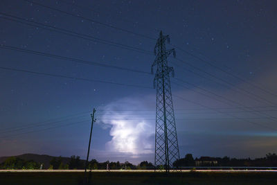 Low angle view of electricity pylon on field against sky