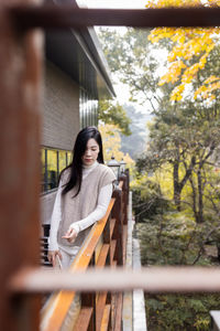 Portrait of young woman sitting on railing