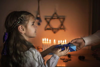 Cropped hand of mother giving gift to cute girl at home