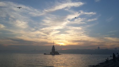 Silhouette sailboat in sea against sky during sunset