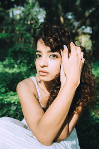 Portrait of young woman sitting against plants