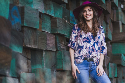 Portrait of smiling woman standing against brick wall