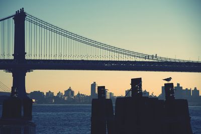 Silhouette of suspension bridge against sky during sunset