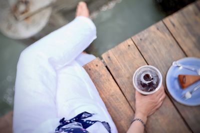 Low section of man holding coffee cup on table