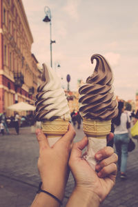 People holding ice cream cone in city