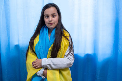 Portrait of young woman standing against wall