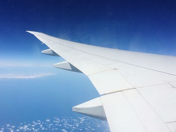 Cropped image of airplane wing against blue sky