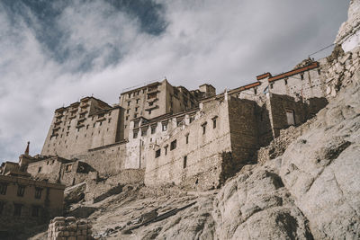 Low angle view of old buildings against cloudy sky