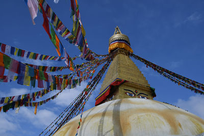 Low angle view of prayer flags hanging in temple against sky
