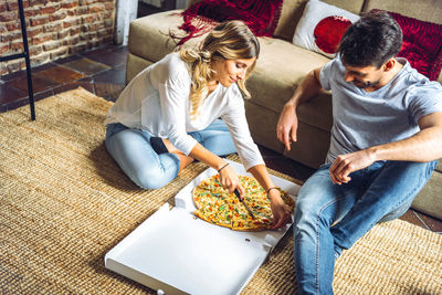 High angle view of friends sitting on sofa at home