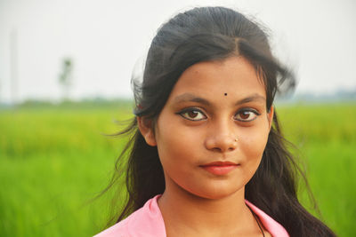 Close-up portrait of teenage girl standing on field