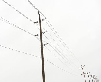 Low angle view of power lines against clear sky