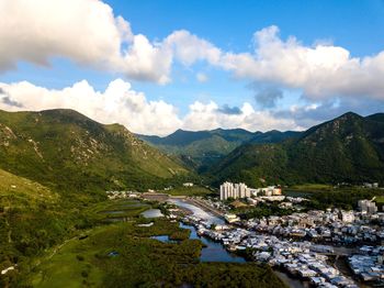 Scenic view of townscape by mountains against sky