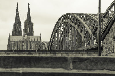 Arch bridge by buildings against sky in city