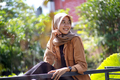 Portrait of a woman wearing a hijab sitting with her eyes looking to the side and smiling