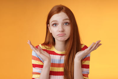 Portrait of teenage girl holding yellow against orange background