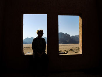 Rear view of man looking through window