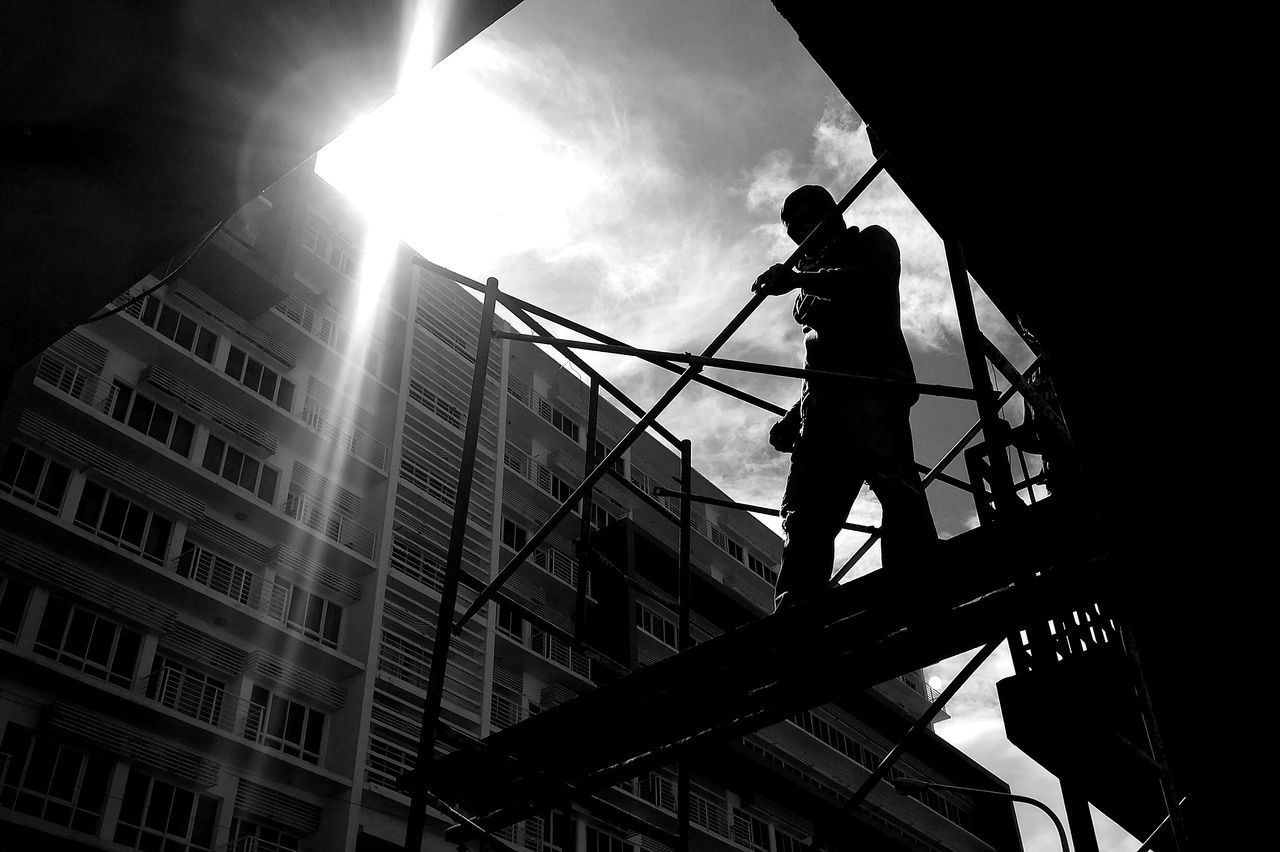 LOW ANGLE VIEW OF MAN WORKING ON BUILDING