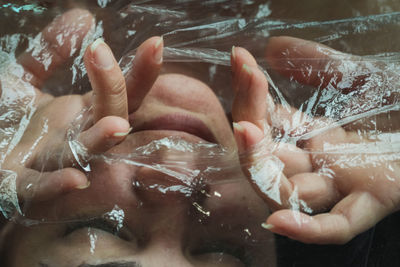 Close-up of woman tearing up plastic to breath 