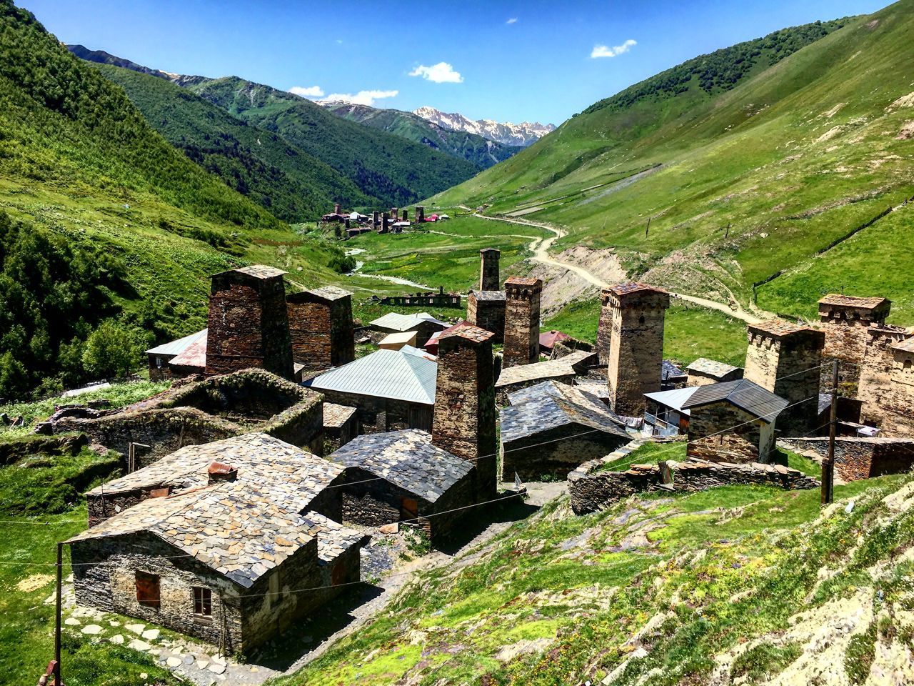 mountain, architecture, built structure, nature, landscape, sky, scenics - nature, grass, plant, beauty in nature, day, no people, building exterior, green color, environment, building, mountain range, tranquility, land, tranquil scene, outdoors, stone wall