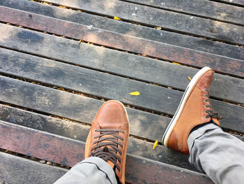 Low section of person wearing shoes on wooden floor