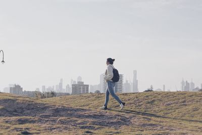 Full length side view of woman walking on field against sky