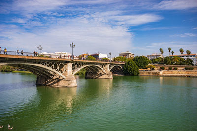 Arch bridge over river against sky in city