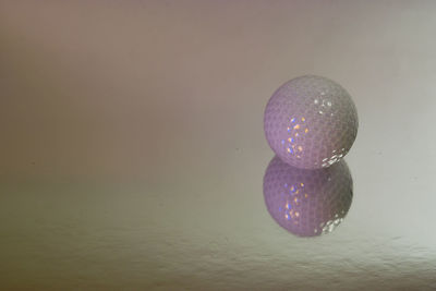 Close-up of purple ball on glass table against wall