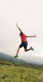 Full length of man jumping on mountain against sky