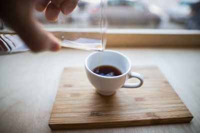 Cropped image of person pouring coffee in cup