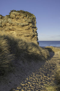 Rock on beach against clear sky