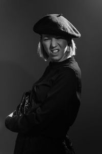 Portrait of mid adult woman standing with purse against gray background