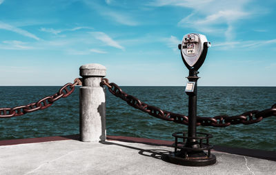 Metallic structure by sea against sky